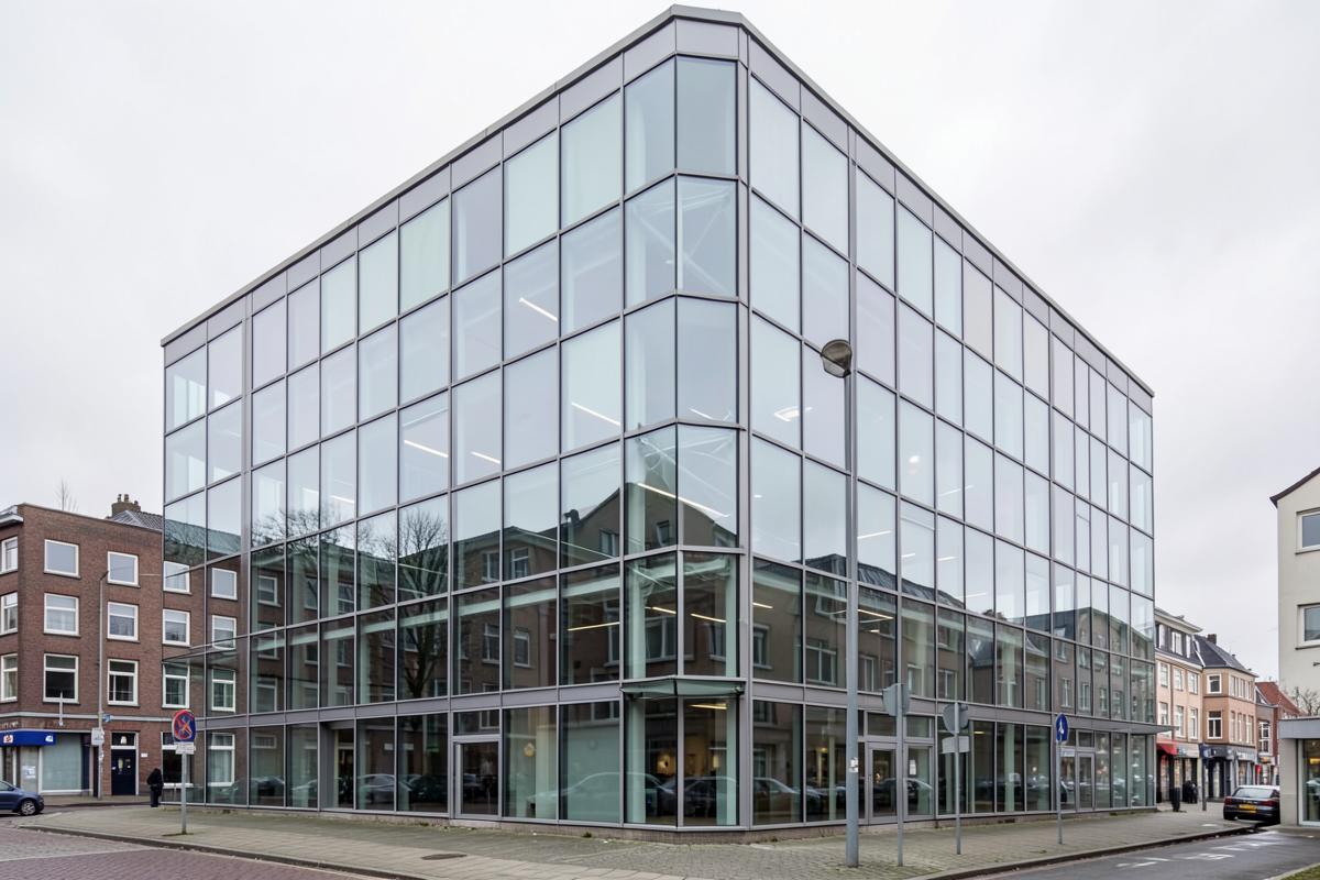 Gläserne Bürogebäudefassade mit gleichmäßigem Fensterraster bei Tageslicht